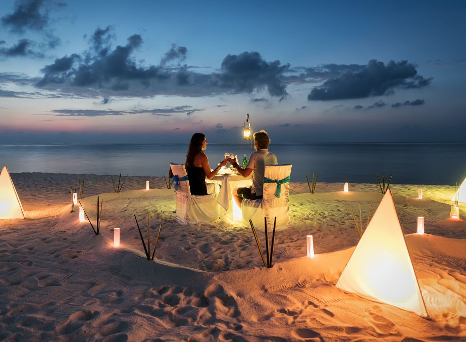 A couple enjoying candlelight dinner on a beach