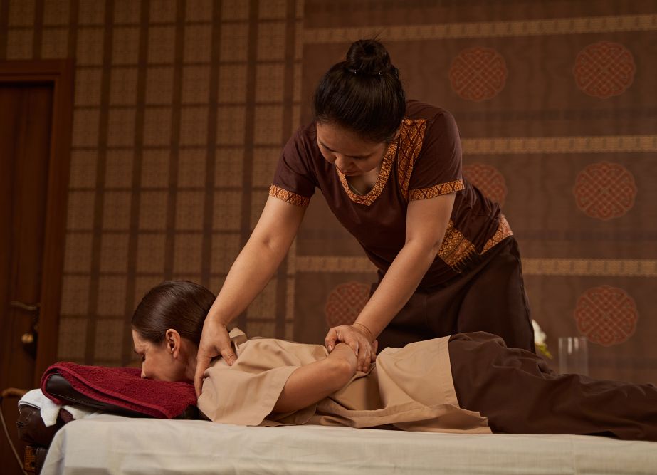 A massage therapist using thumb technique to apply pressure in a traditional Thai massage